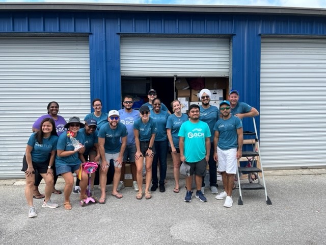 About a dozen of GCM employees wearing the same blue shirt standing in front of the Crisis Management warehouse