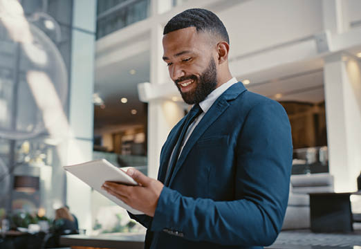 A tan man with a beard in a suit checking some paperwork in a business environment